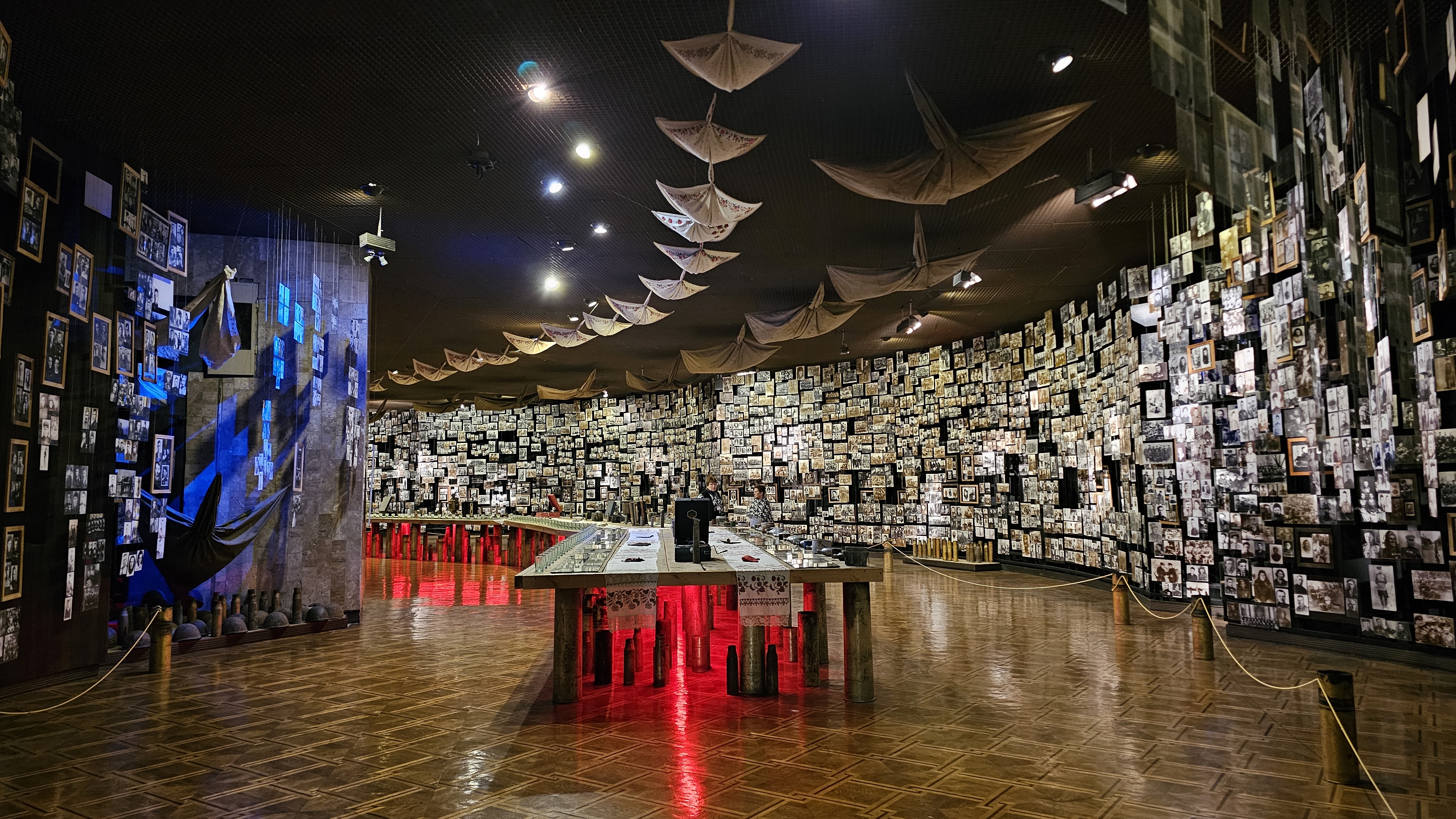 On two curved walls, thousands of pictures are hanging from the ceiling to the floor. In the middle, a banket table