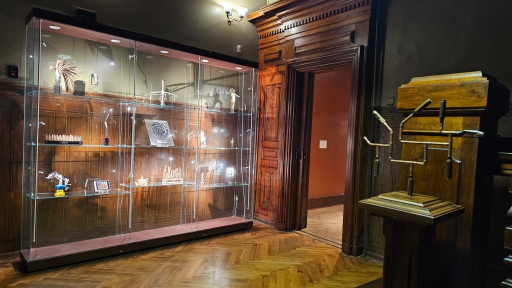 Interior of the Khanenko museum in Kyiv. Dark-green walls, and a vitrine in the background showcasing artifacts gathered on the frontline and reworked by artist Evhen Bal.