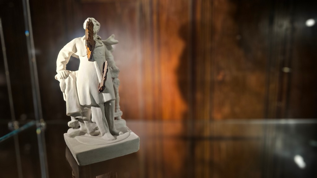 A white porcelain statuette of writer Alexander Pushkin is pierced with rusty explosive shrapnels.