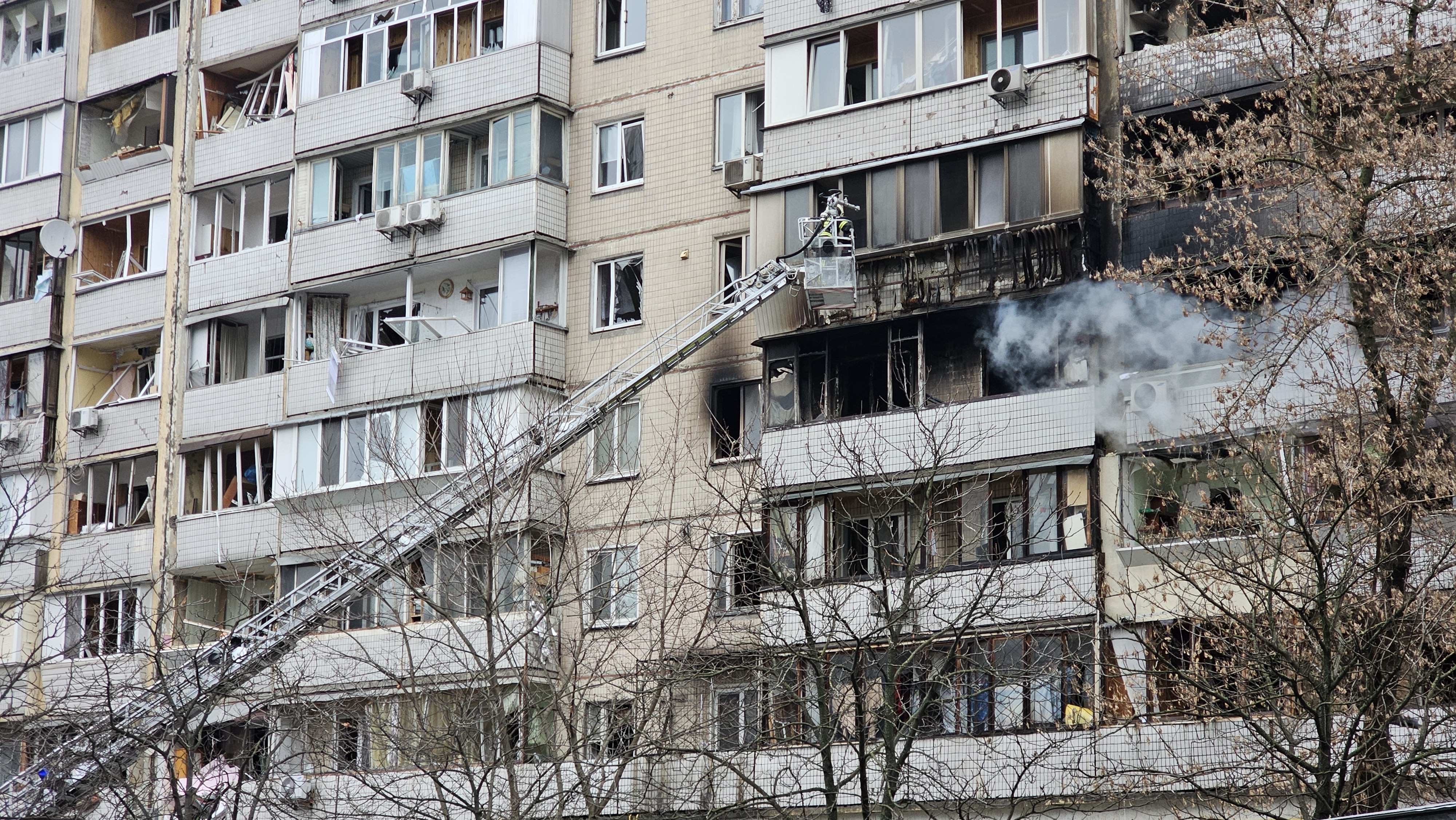 A firefighter is extinguishing a fire on the facade of a residential building in Solomians'kiy district, Kyiv, following a missile strike. All the window glasses are shattered, smoke rises from one of the flats, charred frames are seen.