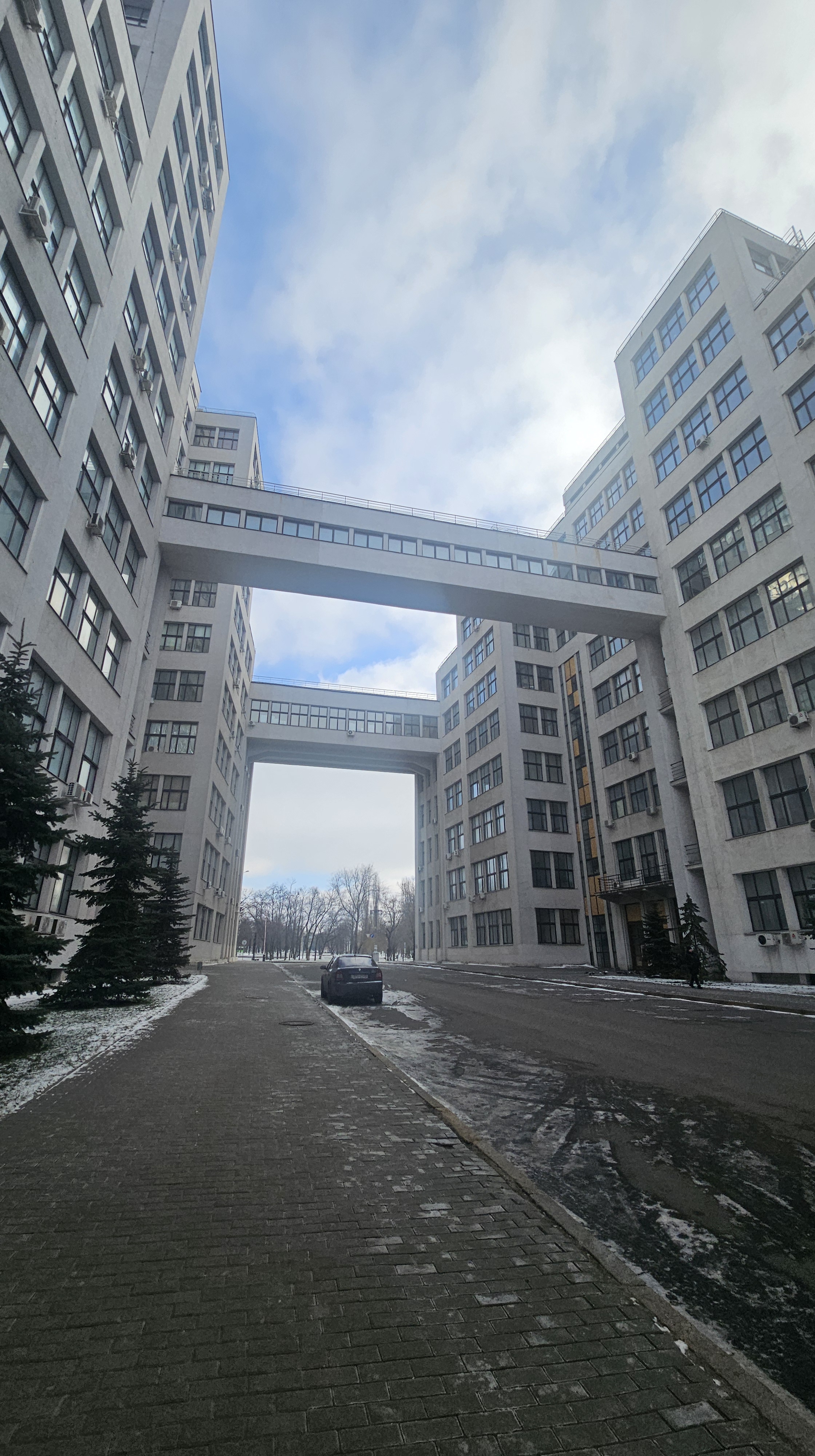 Derzhprom building as seen on February 8th, 2025. Many windows are covered with wooden panels due to russian strikes. Wintry but sunny weather.